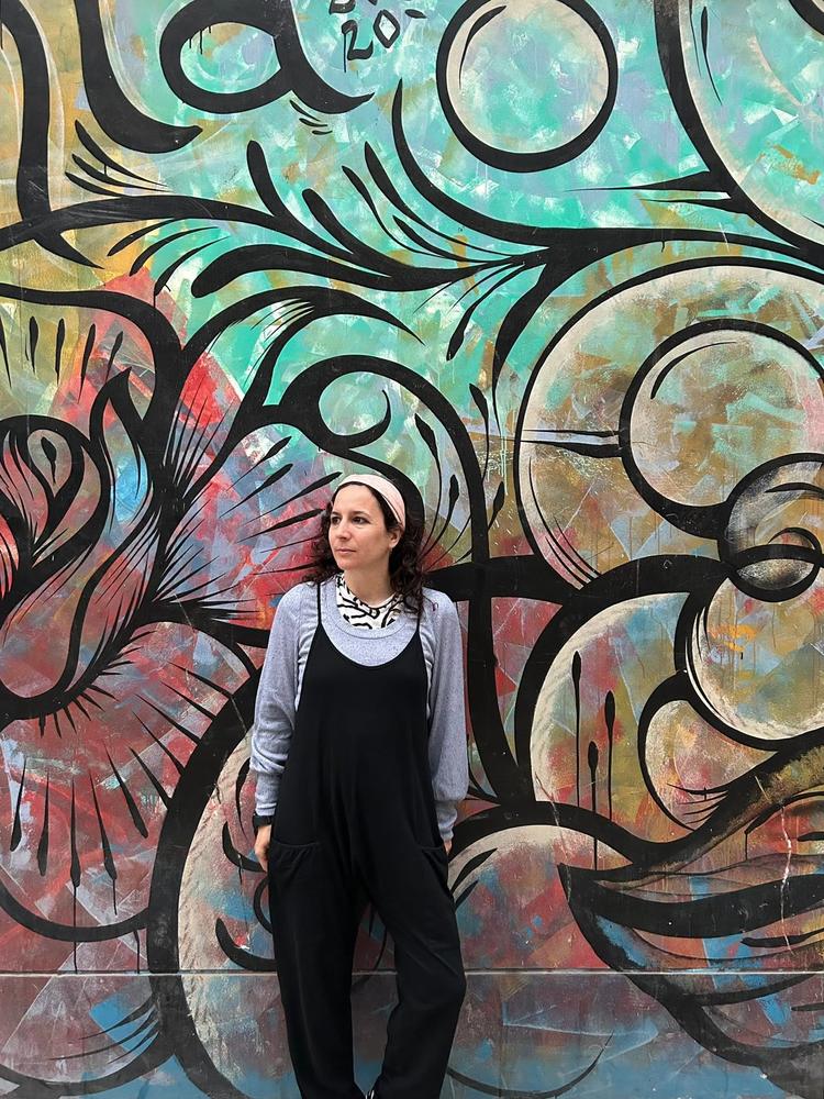 Anais Holgado Lage lying against a colorful mural in Barranco, Lima