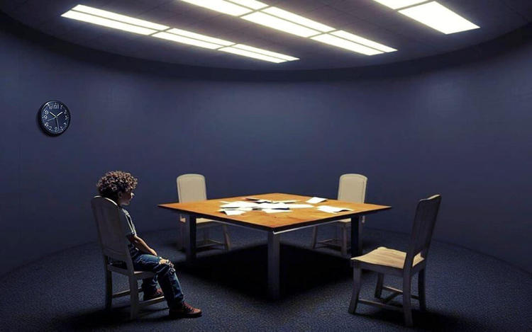Una mesa con una silla vacía y un niño de espaldas en otra silla